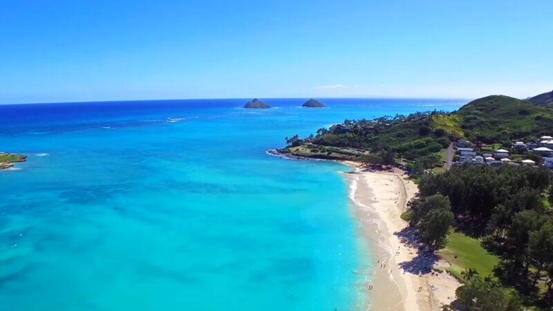 Aerial View of A Populated Hawaiian Beachside Community with Clear Blue Waters and Lush Greenery, Illustrating the Island's Appealing Living Environment