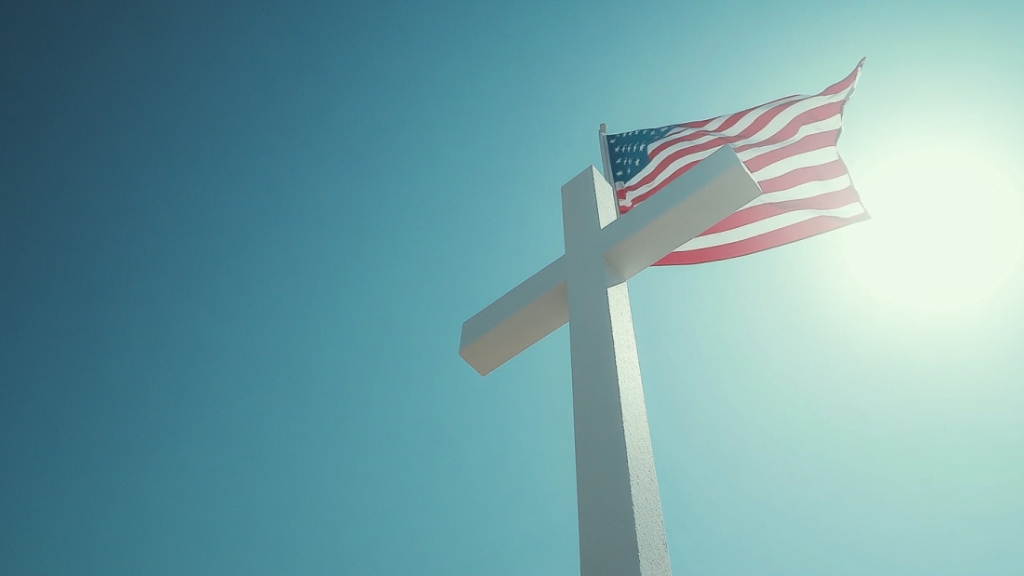 The image shows a cross with the U.S. flag in the background, reflecting the ongoing changes in U.S. Christianity