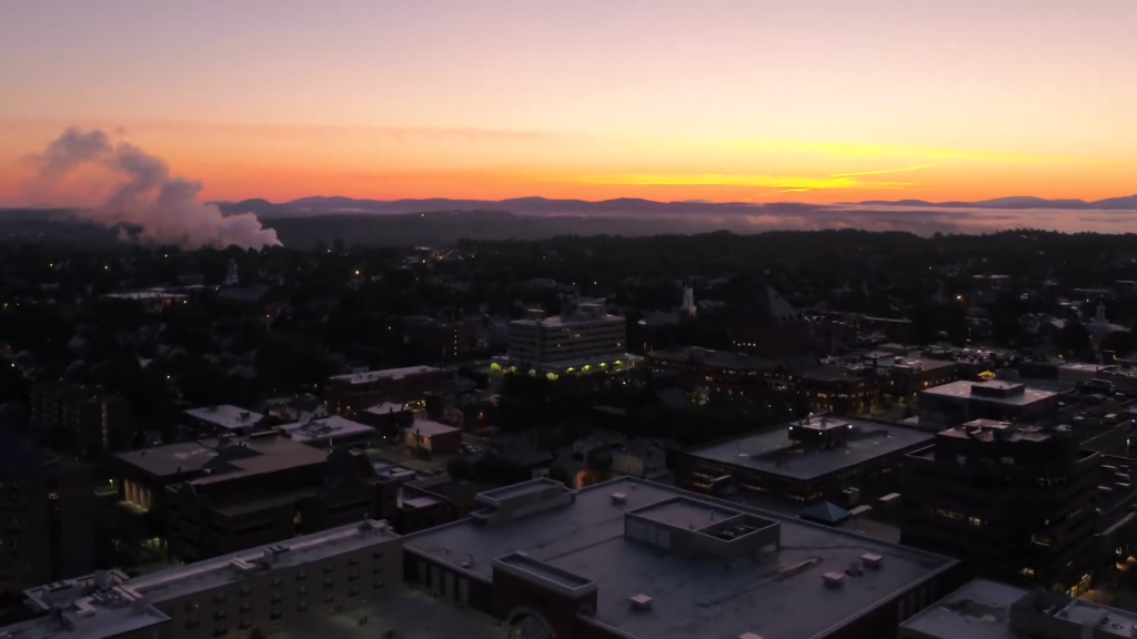 A Sunset View Over Vermont’s Cityscape, with A Mix of Buildings and Distant Mountains