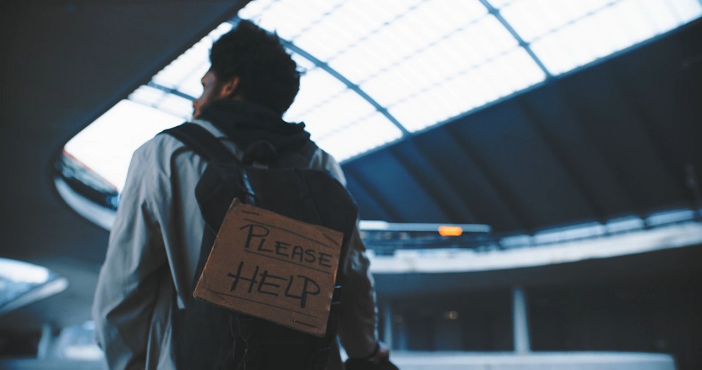 Immigrant man with a sign asking for help, highlighting financial struggles