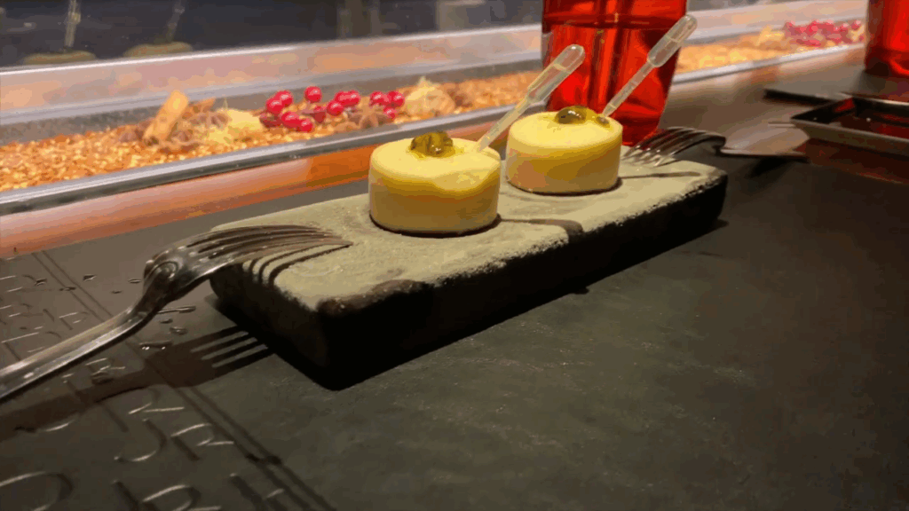 Two elegant amuse-bouches are served on a dark stone platter at L’Atelier de Joël Robuchon in Miami