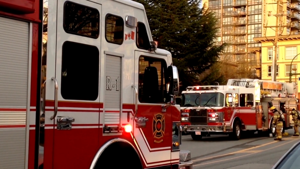 Fire trucks and firefighters respond on a city street during an incident near residential buildings