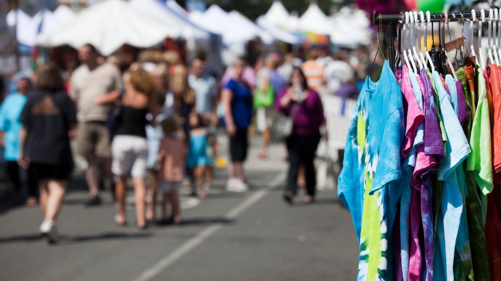 Colorful shirts on display at an outdoor market during community festivals for brand visibility