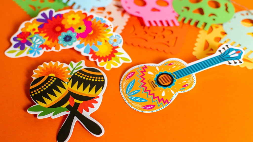 Colorful paper decorations featuring flowers, maracas, and a guitar at cultural and heritage events