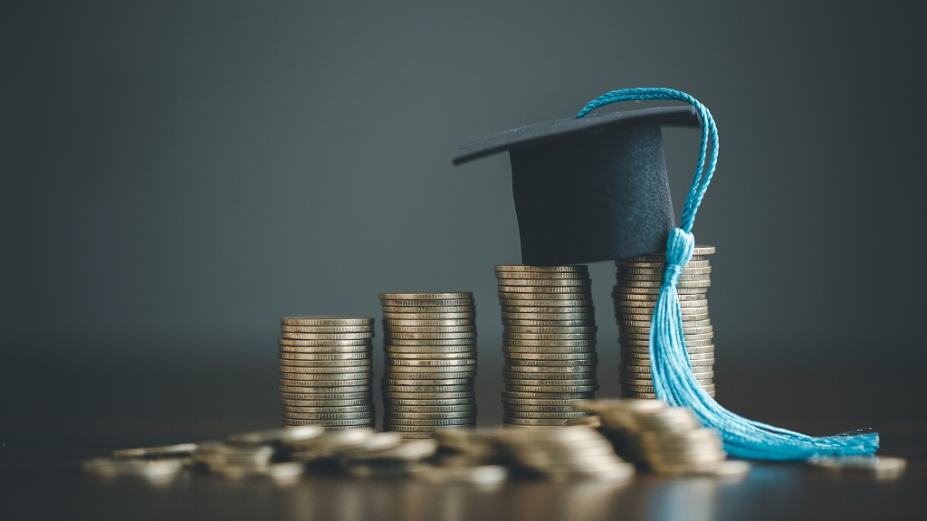 Stacks of coins with a graduation cap show school costs before moving to the US for work