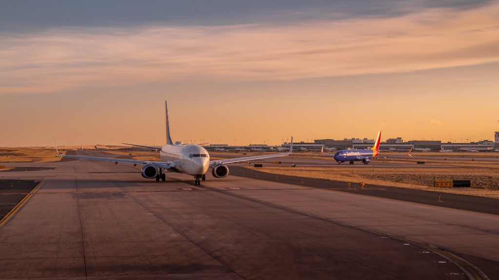 Passenger planes taxiing on a runway at sunset, representing factors that influence aviation safety today