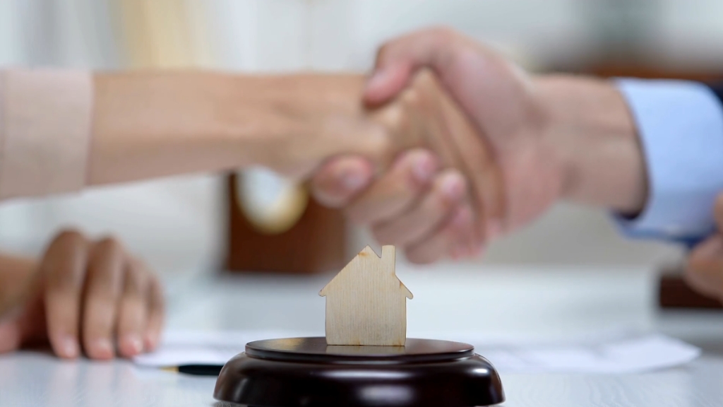 Two people shake hands over a housing deal before moving to the US for work