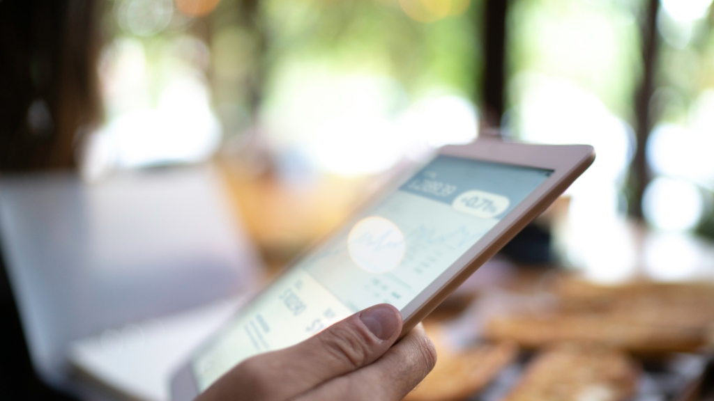 A person holds a tablet displaying financial charts and data, representing income opportunities through digital platforms
