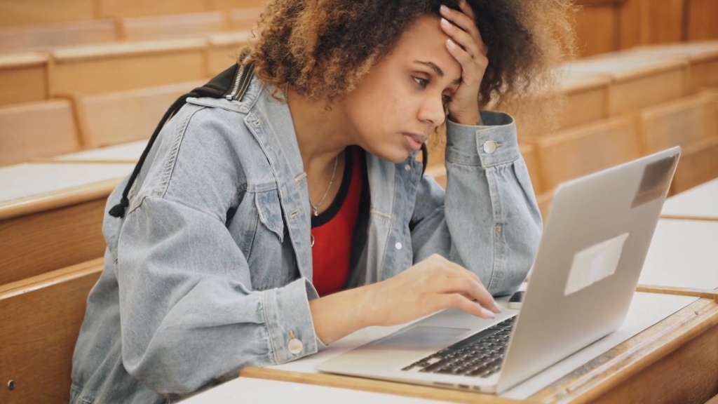 Student stressed at laptop shows the impact of highest student loan debt in U.S. states