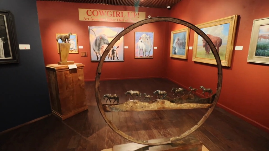 Art exhibit inside the Desert Caballeros Western Museum, featuring western-themed paintings and sculptures