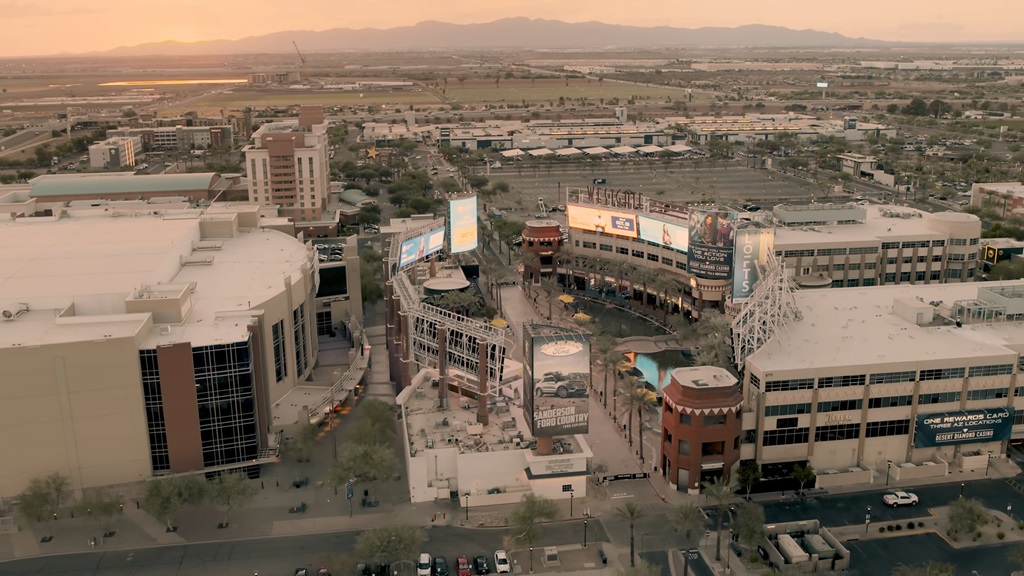 Aerial view of Glendale’s Westgate Entertainment District with arenas, billboards, and nearby developments at sunset