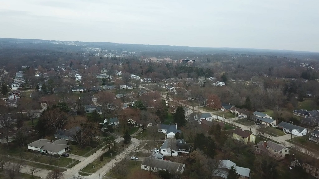 Aerial view of a residential neighborhood in Medina, Ohio, with tree-lined streets, single-family homes, and wooded areas stretching into the distance