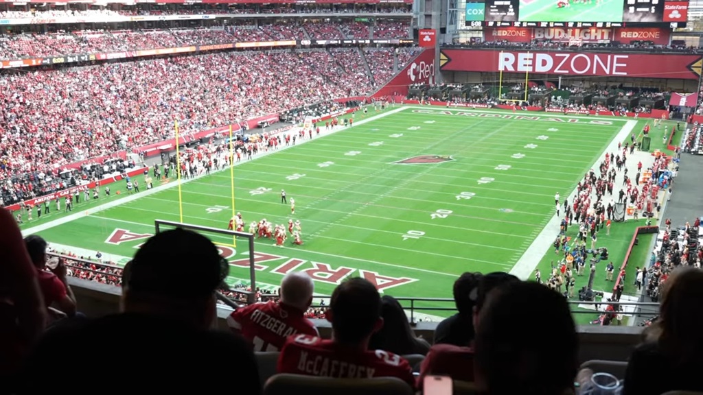 View from the stands at State Farm Stadium during an NFL game, with full crowd and teams on the field
