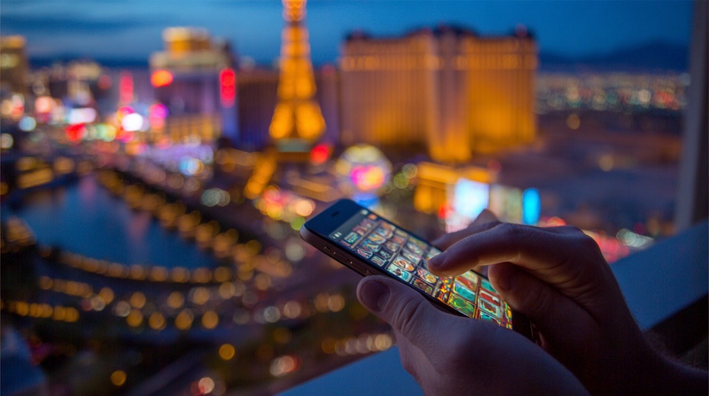Person using a smartphone to play a digital casino game with the Las Vegas skyline blurred in the background