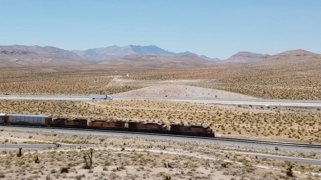 Freight train moving across the desert in Nevada with distant mountains in view, symbolizing inland trade routes connected to Pacific ports
