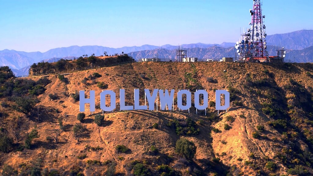 Iconic Hollywood sign on a dry hillside in Los Angeles with communications tower and mountains in the background
