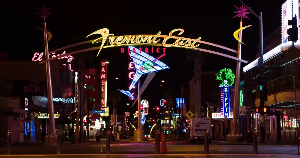 Neon lights of Fremont East District in downtown Las Vegas glowing over unusually quiet streets at night, reflecting the cityโs recent slowdown in tourism