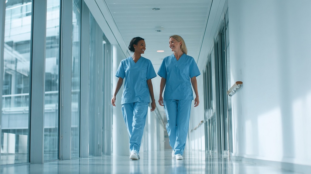 Two nurses walking through a hospital corridor, showing teamwork and satisfaction in modern healthcare careers