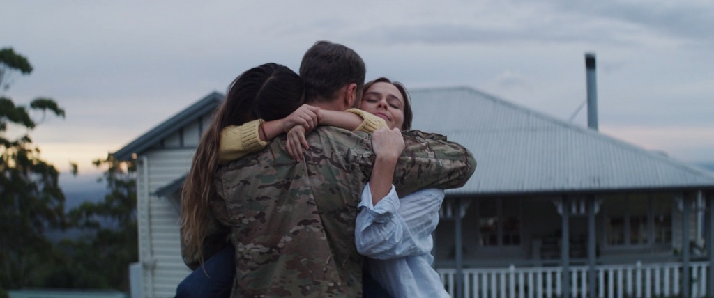 Veteran in military uniform embracing family members outside a home, symbolizing financial security and family support after service.