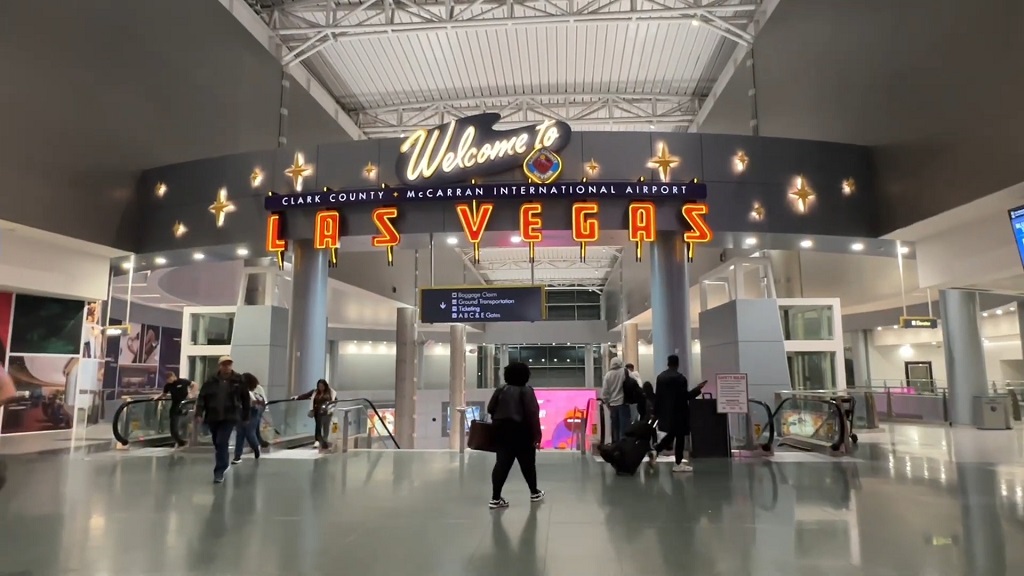 Interior of Harry Reid International Airport in Las Vegas with the illuminated Welcome to Las Vegas sign and travelers walking through the terminal