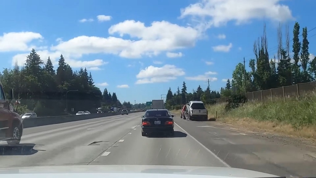 Vehicles traveling on a multi lane highway while a stopped SUV sits on the shoulder, illustrating the everyday risk roadside workers face near fast moving traffic