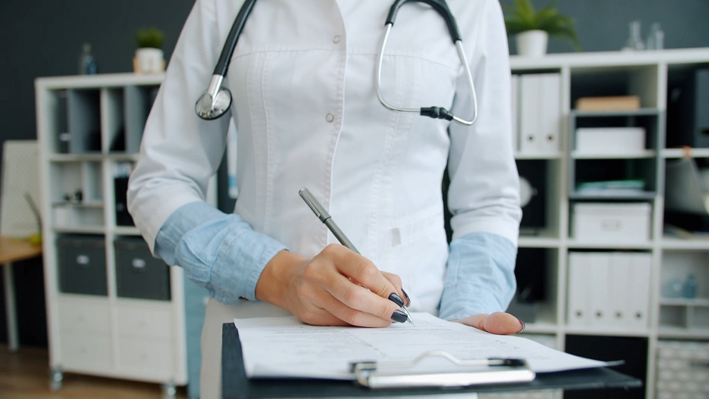Doctor filling out medical forms and treatment documentation after a workplace injury