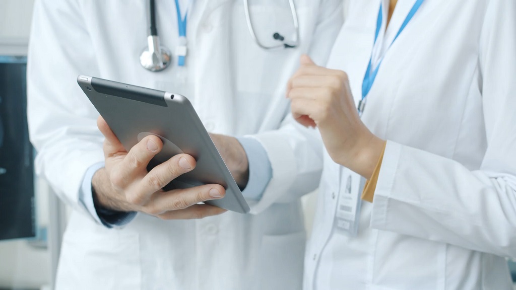 Doctors reviewing patient information on a digital tablet in a modern healthcare setting