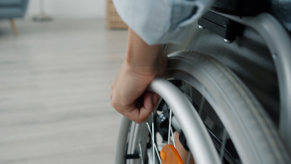 Hand on wheelchair wheel showing long-term disability after a serious workplace injury, workers compensation context