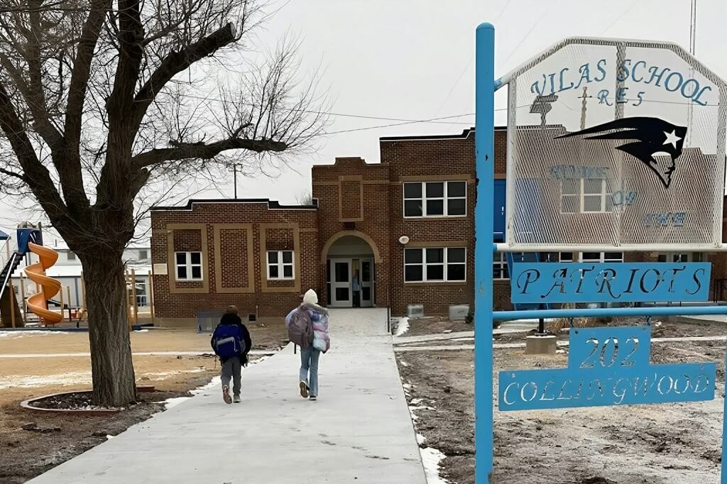 Rural elementary school building in Colorado with students walking toward the entrance during winter