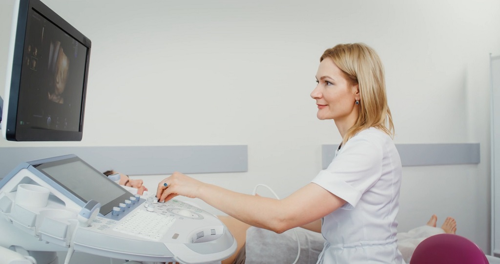 A healthcare professional operates an ultrasound machine during a prenatal checkup, monitoring the pregnancy on screen