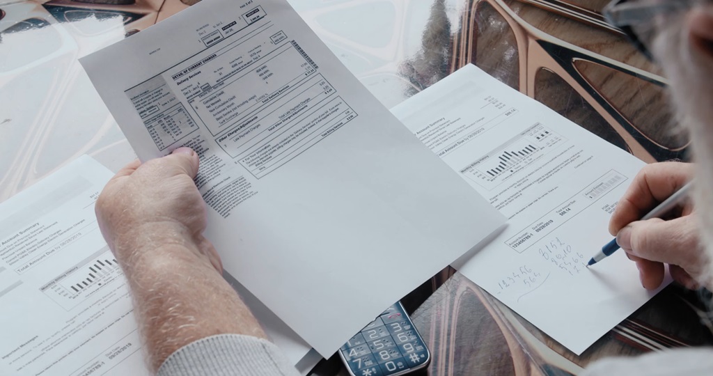 A retiree reviewing financial documents and calculating expenses, representing the impact of taxes and income planning in retirement