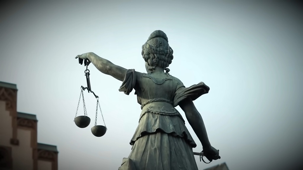 Statue of Lady Justice holding scales outside a courthouse, symbolizing the legal system and judicial process